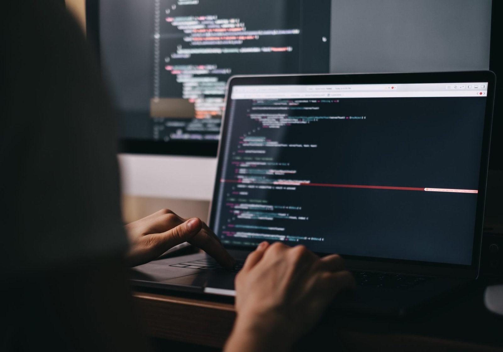 Young caucasian female programmer in glasses writes program code on a laptop computer. home office